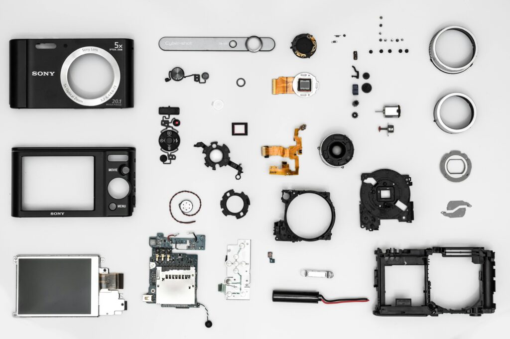 Flat lay of various disassembled camera components on a white background.