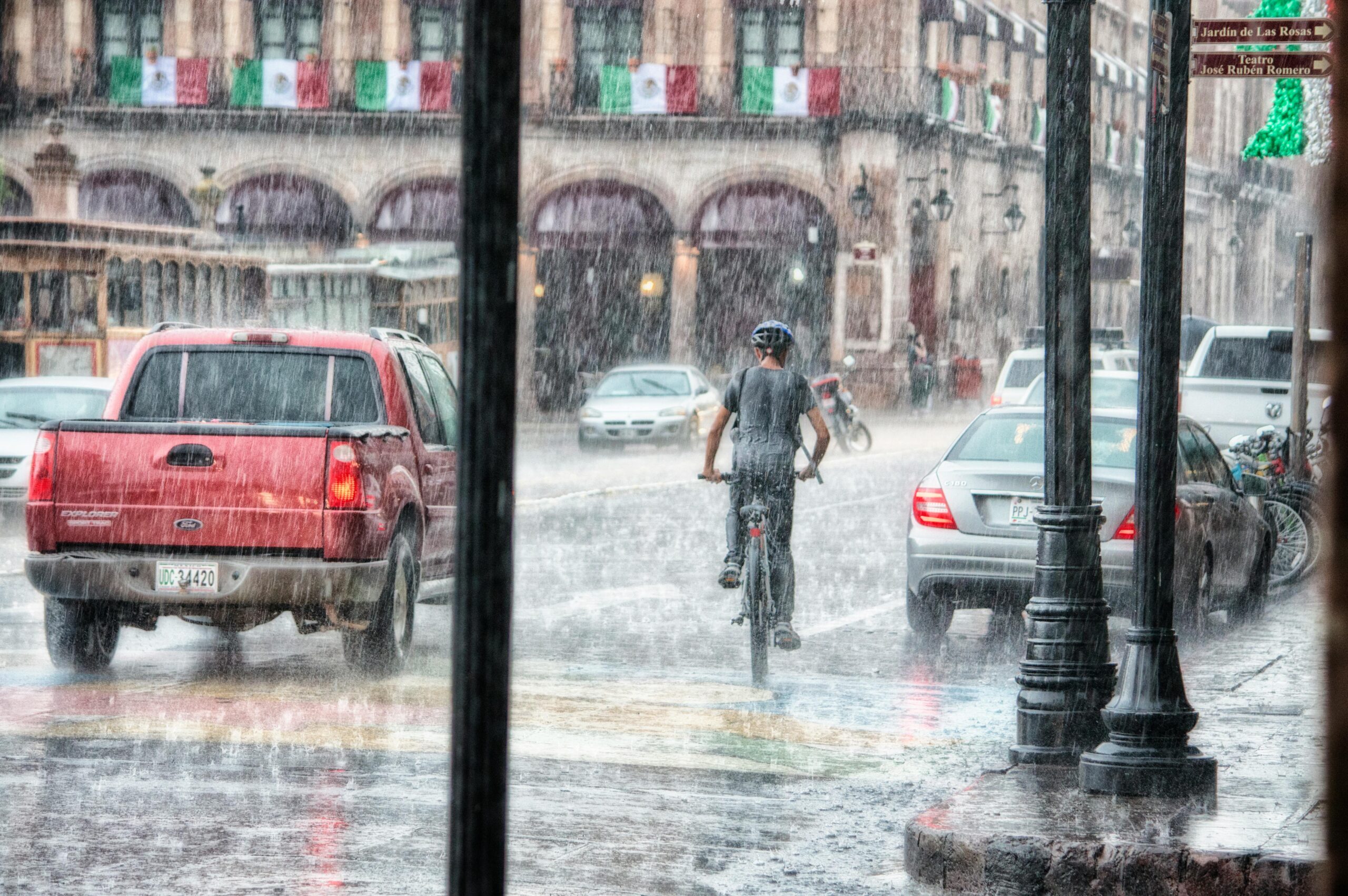 A cyclist rides through heavy rain in Morelia's urban street scene, Mexico.